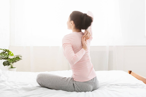 Giovane donna yoga rendendo le mani bloccano dietro la schiena a letto
 - Foto, immagini