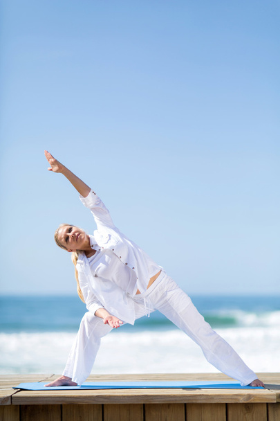 Middle aged woman stretching on beach - Photo, Image