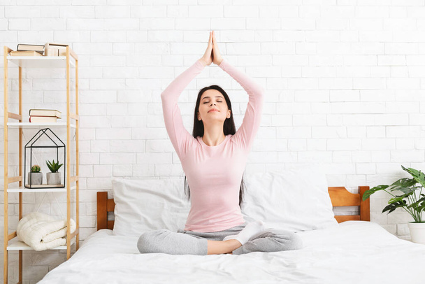 Young woman meditating in bed, free space - Foto, immagini