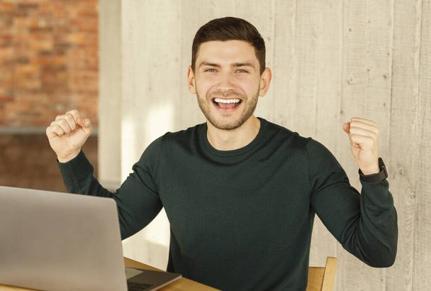 Happy Man Shaking Fists Sitting Celebrating Promotion In Modern Office - 写真・画像