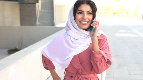 Young Muslim woman wearing hijab using her smartphone. - Video