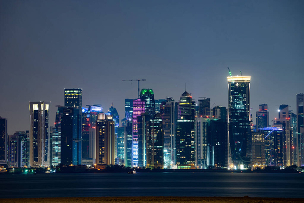 Вібруюча лінія "Доха" в нічний час, як видно з протилежного боку заходу сонця в затоці столиці - Фото, зображення