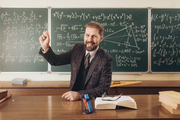 Улыбающийся учитель математики поощряет аудиторию во время лекции
 - Фото, изображение
