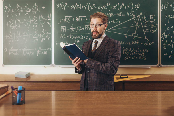 Profesor barbudo en traje y gafas citando un manual
 - Foto, Imagen