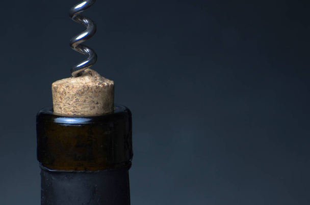 A bottle of wine to be opened. Bottle of wine, cork and corkscrew on a dark background. Close-up. - Photo, Image