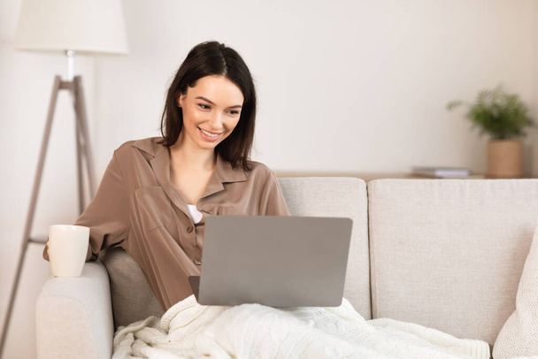 Young woman using laptop lying on the couch - Φωτογραφία, εικόνα