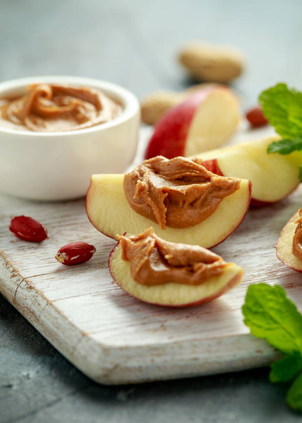 Manteiga de amendoim e maçã para petiscar. na placa de madeira branca
 - Foto, Imagem