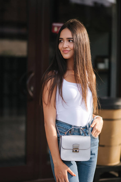 Young and beautiful woman stand outside in front of coffee shop. Attractive brunette in white shirt - Φωτογραφία, εικόνα