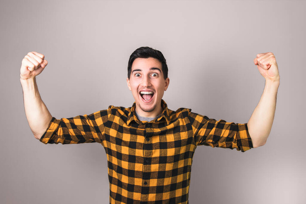winner. happy excited man in yellow shirt celebrating a winning gesturing with both arms - 写真・画像