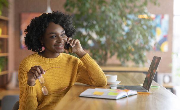 Cheerful black woman talking to business partners on phone - Fotó, kép