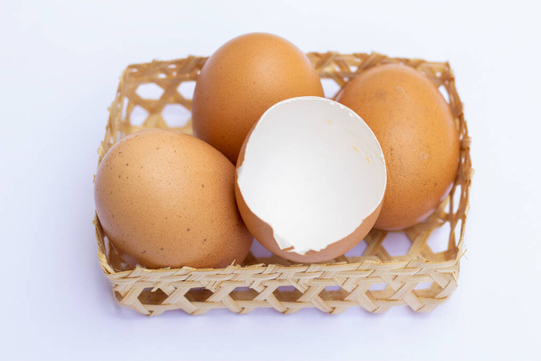 Brown chicken eggs are placed in bamboo trays. With an eggshell on a white background - Photo, Image