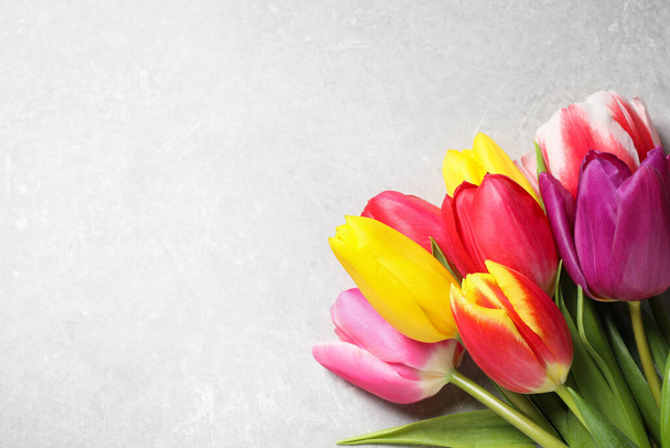 Beautiful spring tulips on light grey stone table, flat lay. Space for text - Foto, Imagem