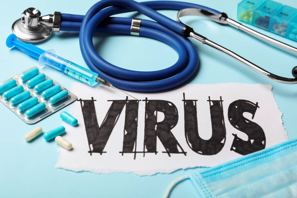 Word VIRUS, stethoscope and medicines on light blue background, closeup - Photo, image