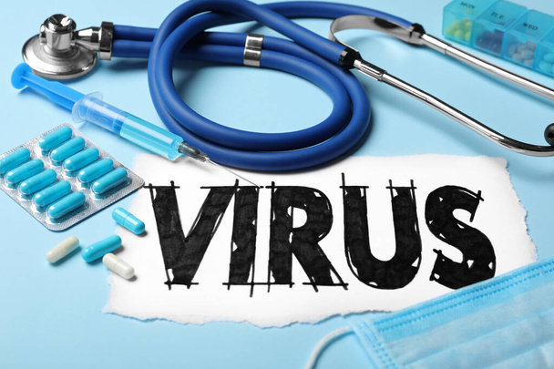 Word VIRUS, stethoscope and medicines on light blue background, closeup - Zdjęcie, obraz