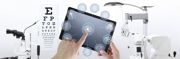 hands touch screen of digital tablet with ophthalmologist and optometrist icons symbols, ophthalmology and optometry equipment on background - Photo, Image