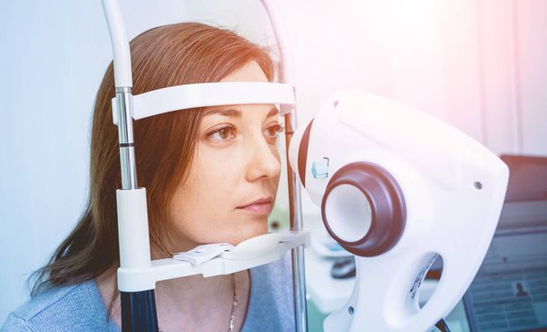 Doctor examining womans eyes with a measurement machine. - Valokuva, kuva