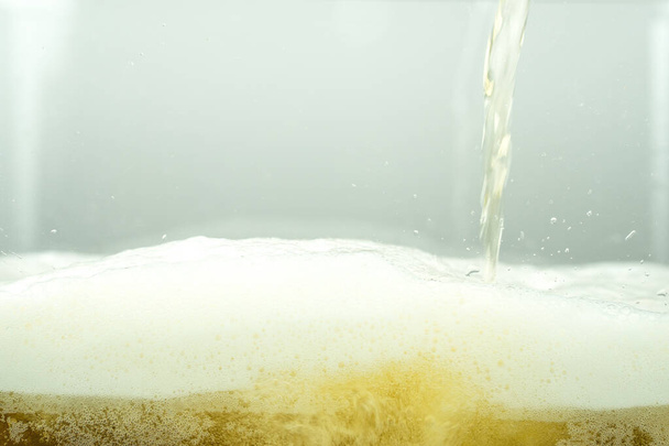 Primo piano di fresco spruzzi di birra lager isolato su sfondo bianco con bolle realistiche & schiuma in vetro. Versare birra artigianale dorata sulla forma curva onda vista frontale schiuma texture per pub & bar menu design
 - Foto, immagini