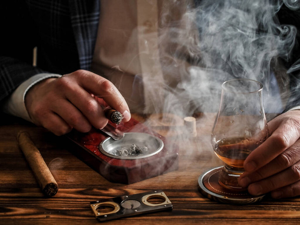A well-dressed man at a bar drinks single malt whisky and smokes a cigar - Fotoğraf, Görsel