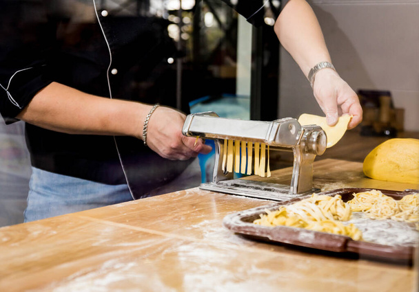 Chef rolling dough with a pasta machine. Pasta maker machine.  - Foto, Bild