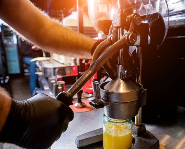 Espremedor manual de metal. Preparação de suco de laranja espremido na hora
 - Foto, Imagem