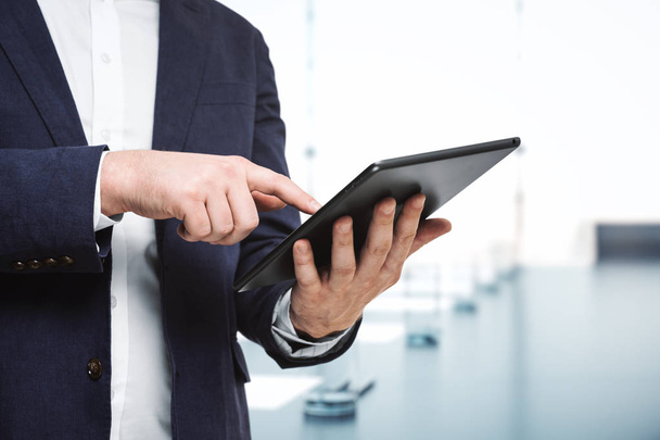 Businessman holds digital tablet and clicks on screen in modern office, close up. Search concept - Foto, Bild