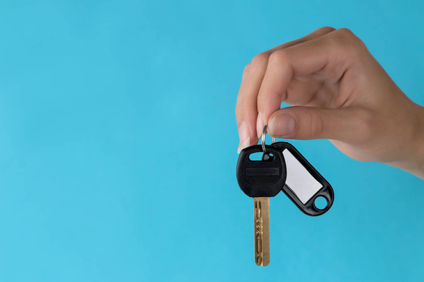 Home purchase concept. Keys with a keychain with place for text in hand on a blue background - Foto, imagen