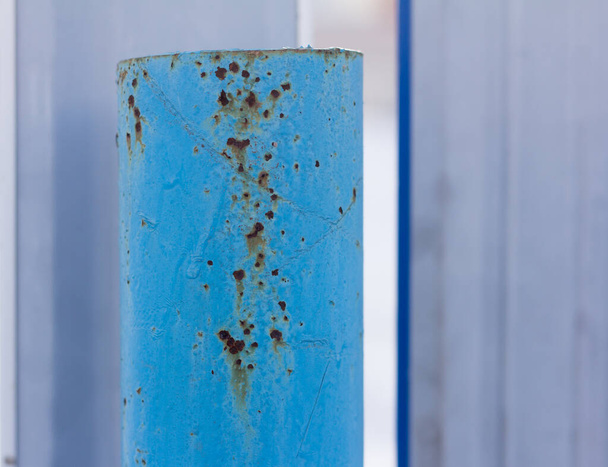 A rusty metal pipe, Rust through the blue paint on an iron post. - Photo, Image