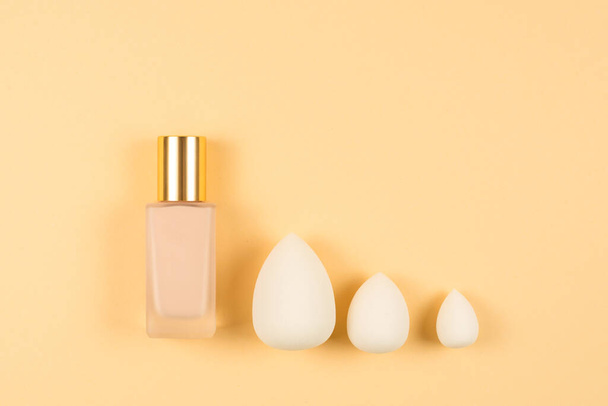 Small, medium and large  white beauty blender and makeup foundation on beige background. Top view.  - Photo, Image