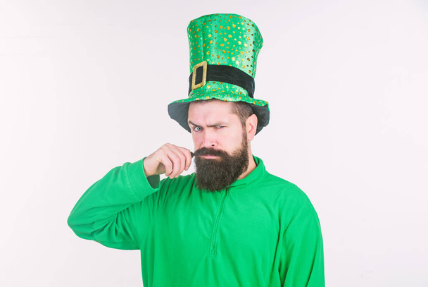 Twirling his moustache. Happy saint patricks day. Bearded man celebrating saint patricks day. Hipster in leprechaun hat and costume. Irish man with beard wearing green - Fotó, kép