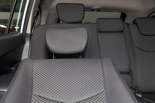 Upholstery of the seats of the passenger compartment with headrest of a luxury car with black fabric material in a workshop for hauling vehicles with a seam of thread. - Photo, Image