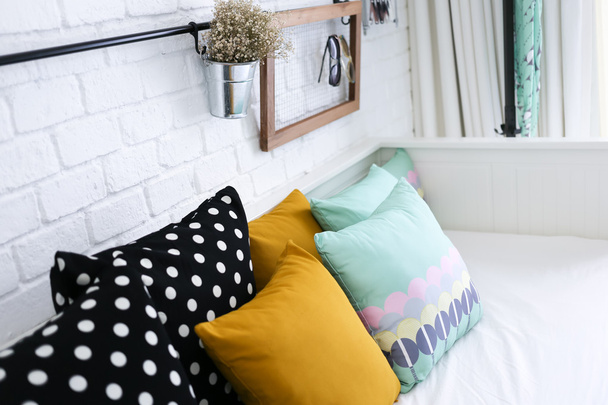 színes párnák a kanapén, fehér tégla fal háttérben - Fotó, kép