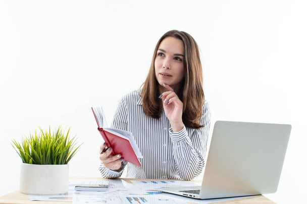 Ein Mädchen in Bürokleidung sitzt an ihrem Schreibtisch und studiert ihre Arbeitspläne - Foto, Bild