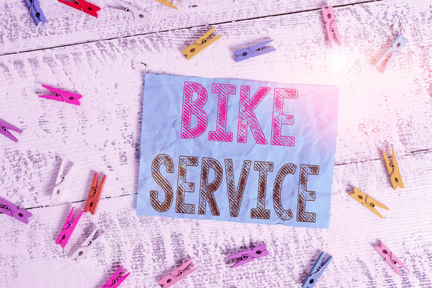 Nota de escritura mostrando Bike Service. Foto de negocios que muestra el mecanismo de limpieza y reparación de bicicletas para mantener el mejor estado Pinza de ropa de color rectángulo cuadrado en forma de papel blanco fondo de madera
. - Foto, Imagen
