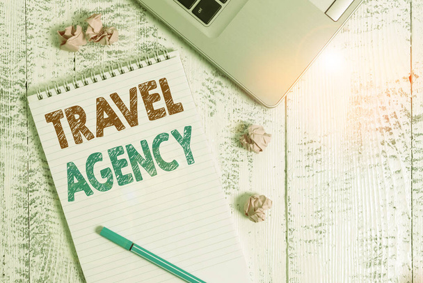 Conceptual hand writing showing Travel Agency. Business photo showcasing Agency that makes the necessary arrangements for travelers Laptop ruled spiral notepad crushed paper balls wooden table. - Photo, Image
