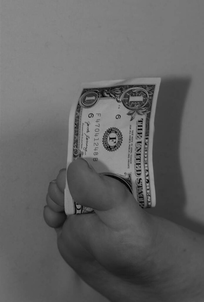 Черно-белое изображение человеческой ноги, держащей долларовую купюру между пальцами ног
 - Фото, изображение