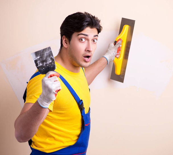 Empleado joven contratista aplicando yeso en la pared - Foto, Imagen