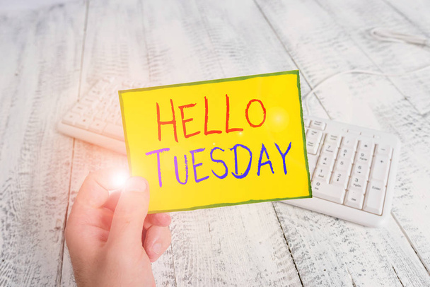 Handwriting text Hello Tuesday. Concept meaning a greeting or warm welcome to the third day of the week man holding colorful reminder square shaped paper white keyboard wood floor. - Photo, Image
