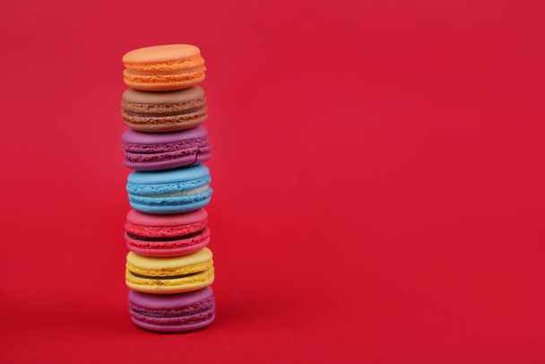 colored french macaroons on top of each other on a red background - Фото, изображение