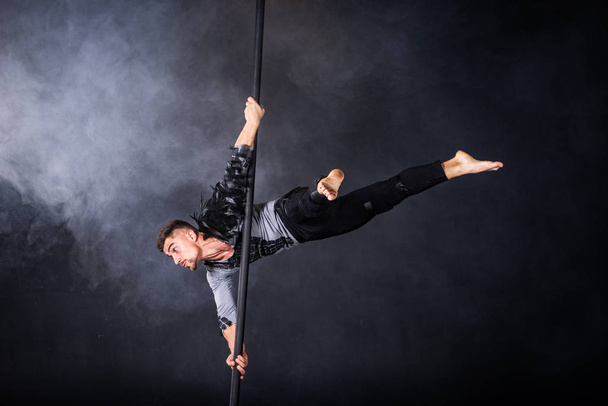 Performance concept. Man hanging on chinese pole. Athlete performing flying pole - Photo, Image
