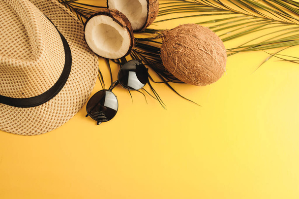 Summer composition. Tropical palm leaves, hat, glasses and broken coconut on a sandy background. The concept of the summer season, parties and heat. Flat lay, top view, copy space - Фото, зображення