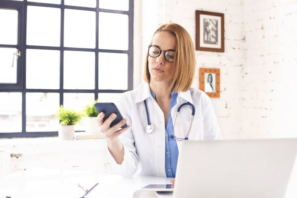  middle aged female doctor using her mobile phone  - Photo, Image