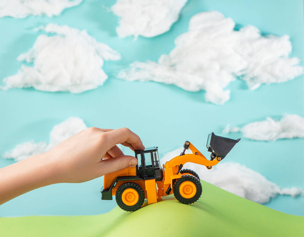 Dziecko bawiące się zabawką przejeżdżające przez papierowe wzgórza. - Zdjęcie, obraz