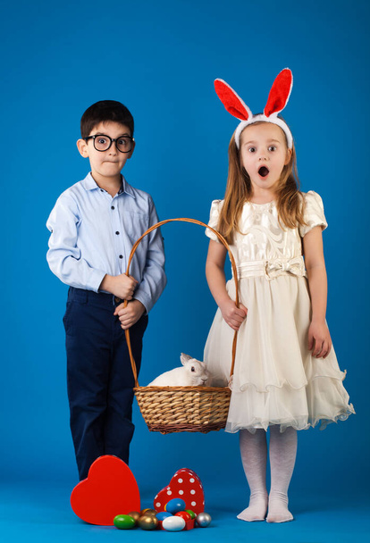 可愛いです男の子と女の子とともに白いウサギでバスケットでイースターエッグ - 写真・画像