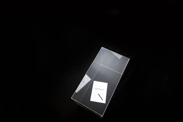 contract is under control. A contract printed on paper and a pen lies in a glass box - Фото, изображение