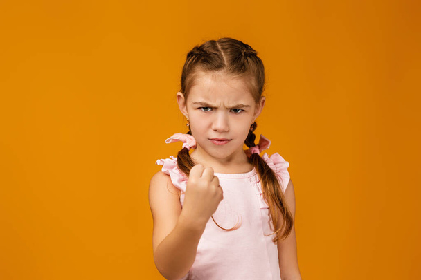 angry little child girl in dress raising fist - Foto, afbeelding