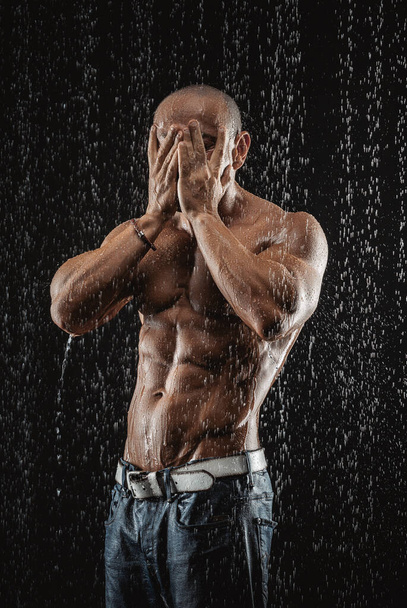 very muscular handsome athletic man in the rain - 写真・画像
