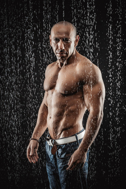 very muscular handsome athletic man in the rain - Фото, зображення