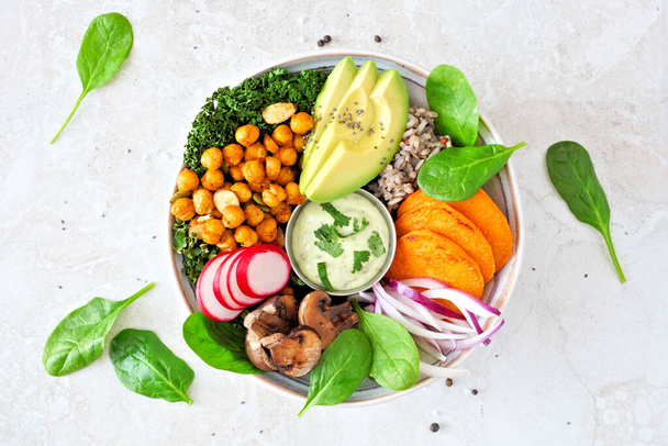 Здоровый веганский обед с авокадо, сладким картофелем, капустой и овощами. Вид сверху на белокаменном фоне. Концепция здорового питания
. - Фото, изображение