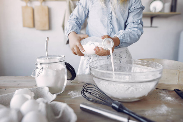 Маленька дівчинка в білому шапці готує тісто для печива
 - Фото, зображення