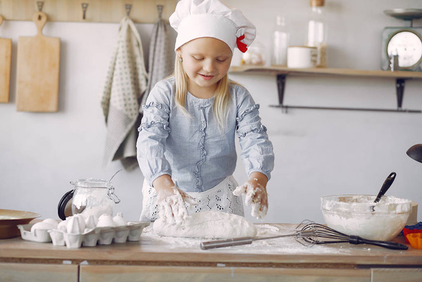 Little girl in a white shef hat cook the dough for cookies - Photo, Image